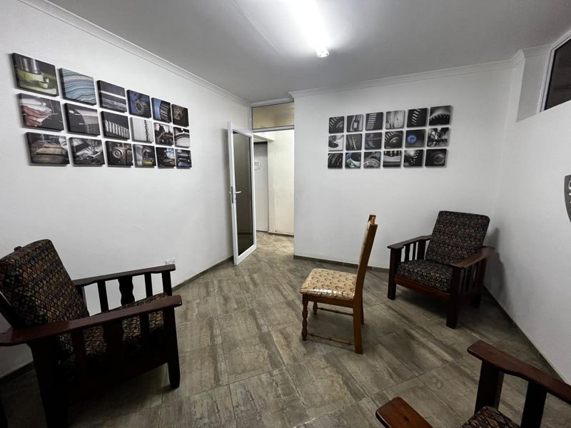 A functional office or reception area featuring tiled flooring, neutral walls, and a coved ceiling with overhead lighting.