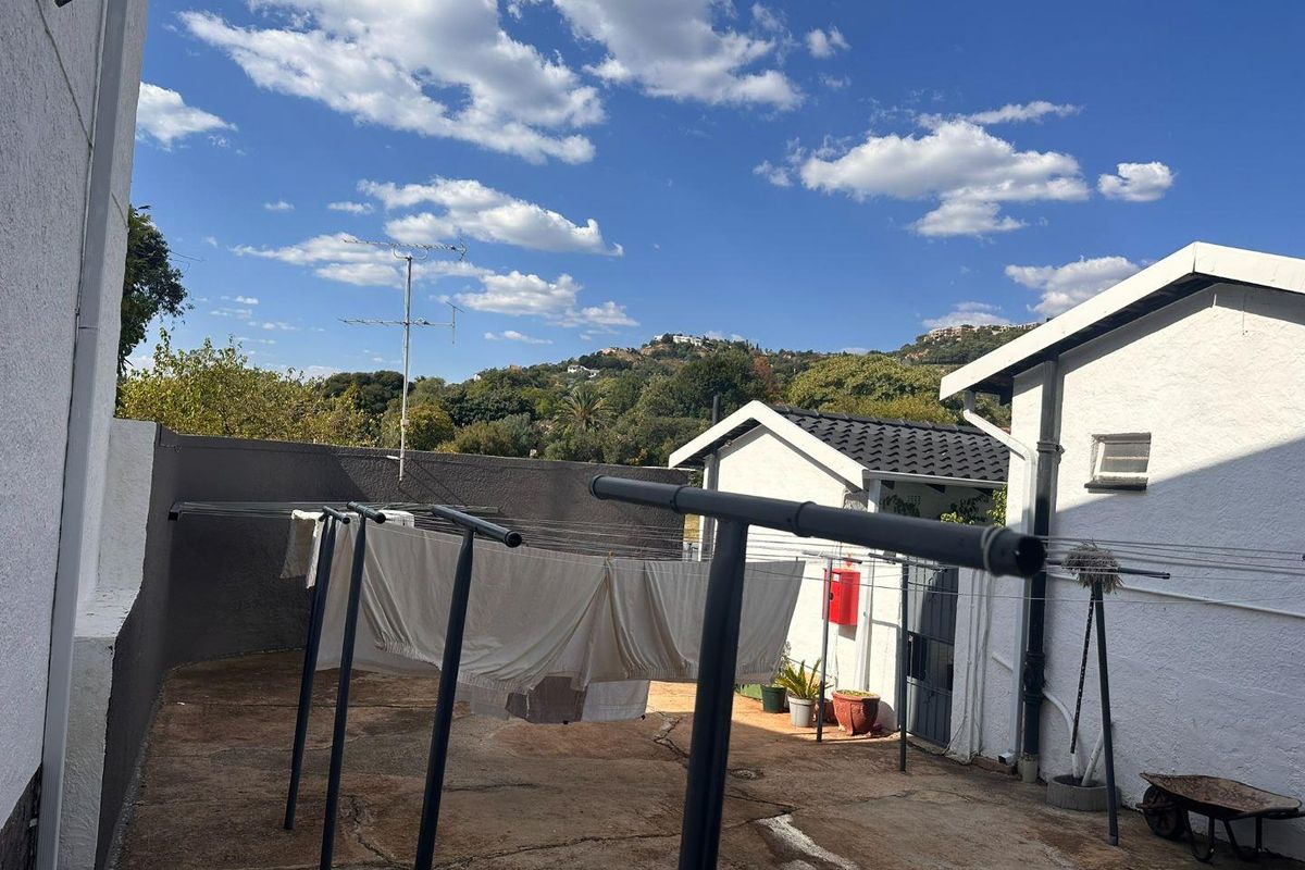A rear courtyard area featuring concrete paving, boundary walls, and external utility fixtures with views of the surrounding landscape.