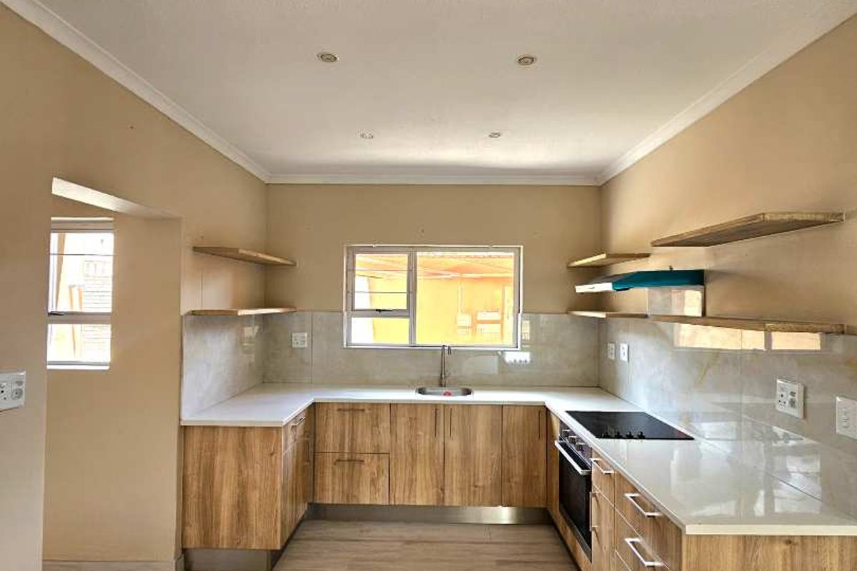 Modern U-shaped kitchen featuring wood-finish cabinetry, stone countertops, built-in oven, electric hob, and floating shelving in a clean, open-plan layout.