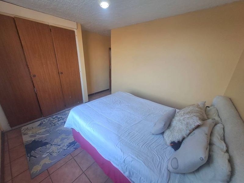 A bedroom featuring built-in wooden cupboards and tiled flooring, offering a functional space with neutral wall tones.