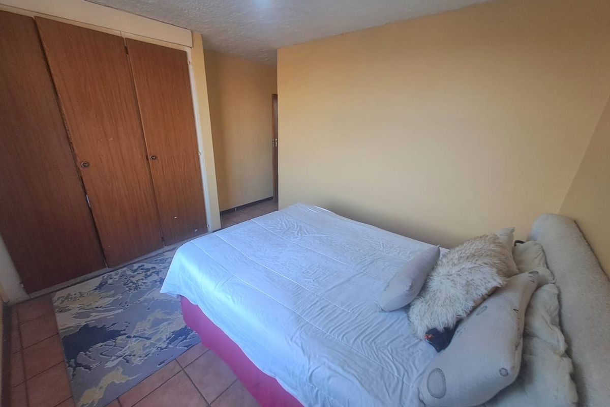A bedroom featuring built-in wooden cupboards and tiled flooring, offering a functional space with neutral wall tones.