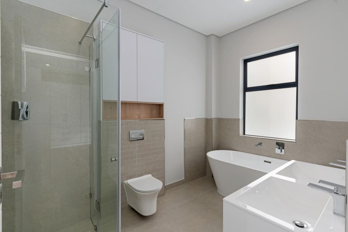 Modern bathroom featuring a glass-enclosed shower, a freestanding bathtub, a wall-mounted toilet, and a double vanity with contemporary fixtures.