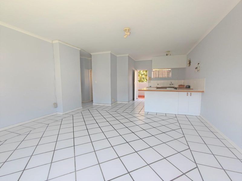 An open-plan living and kitchen area featuring tiled flooring and basic cabinetry, offering a blank canvas for renovation and modern styling.