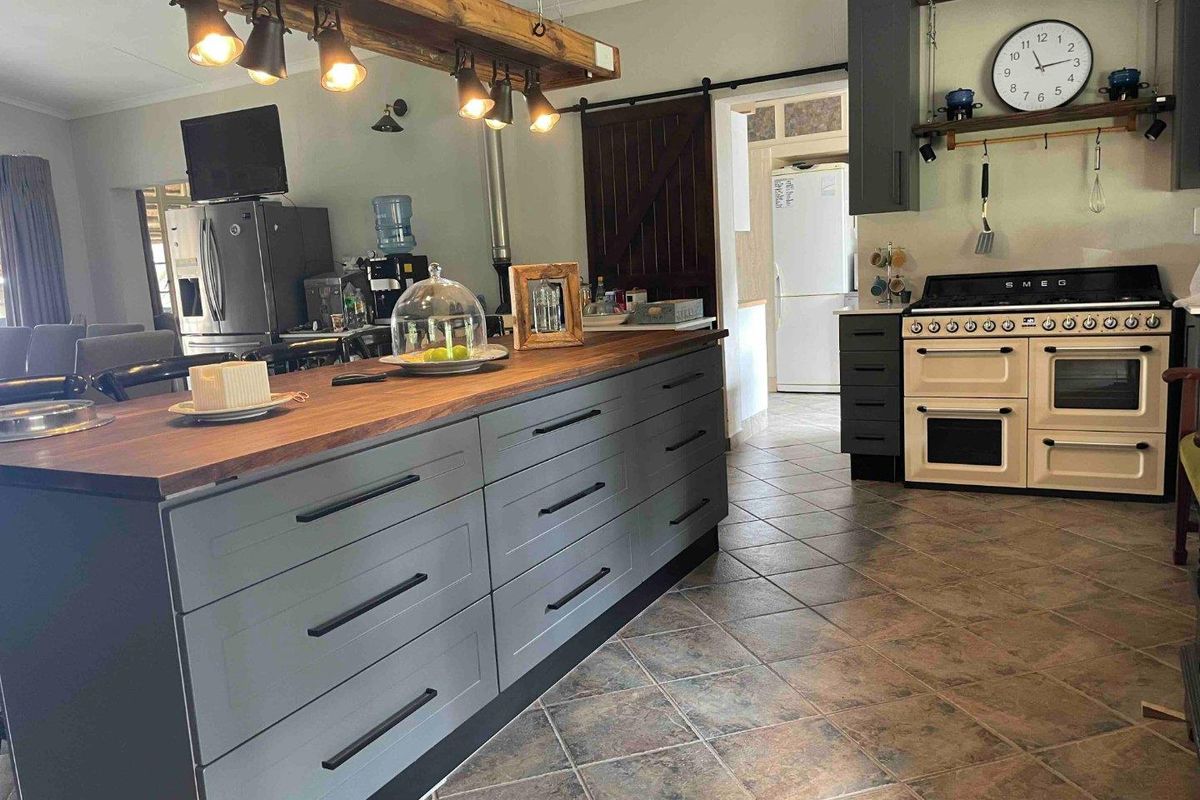 Modern kitchen featuring a large central island with timber countertop, dark grey cabinetry, and a classic cream-colored freestanding range cooker.