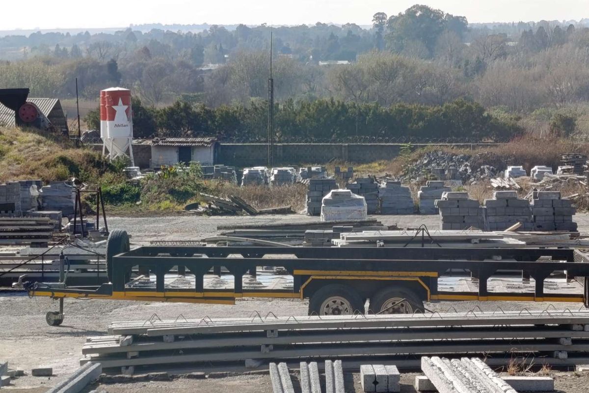 An elevated view of a small holding property featuring industrial storage, concrete materials, and a water silo on the premises.
