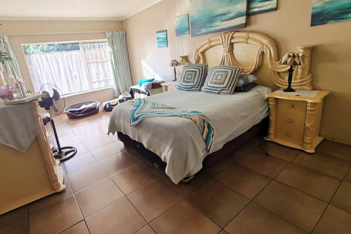 A spacious bedroom featuring large windows, tiled flooring, and a neutral color palette, offering a comfortable and functional living space.