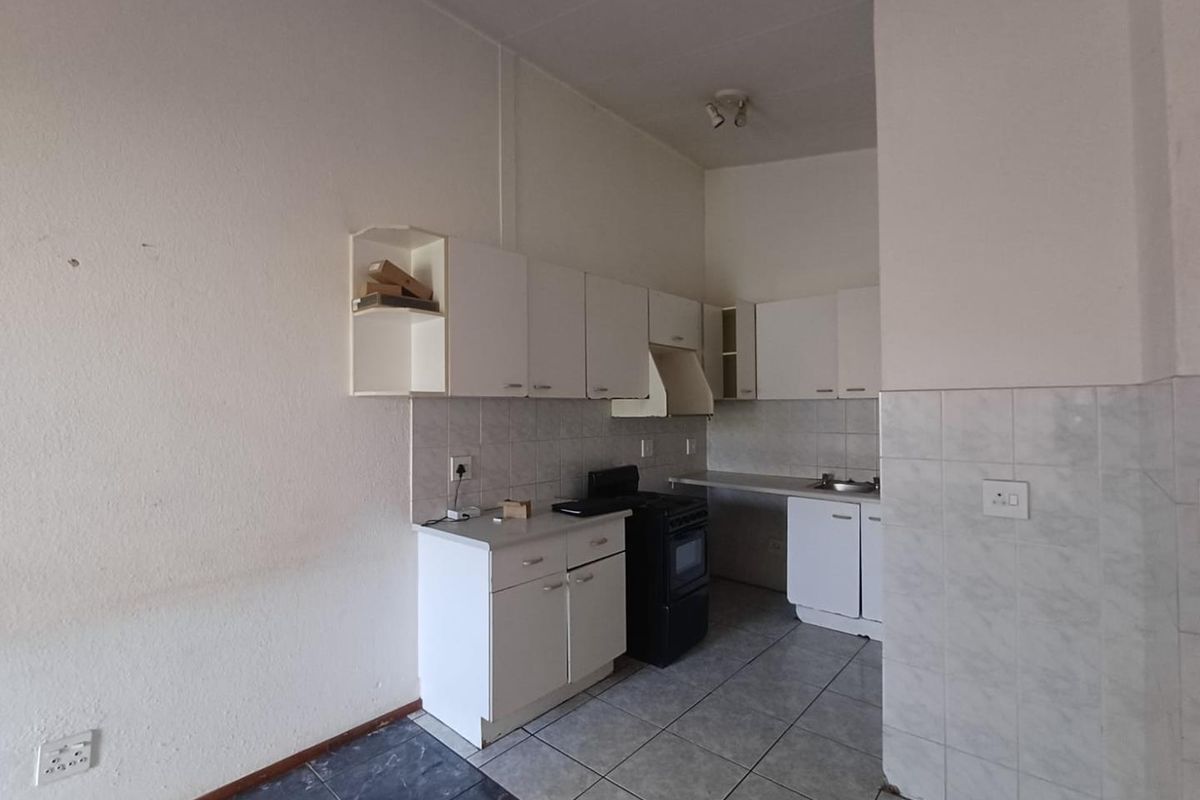 A functional, empty kitchen featuring white cabinetry, a tiled backsplash, and a freestanding stove, offering a blank canvas for modern renovation.