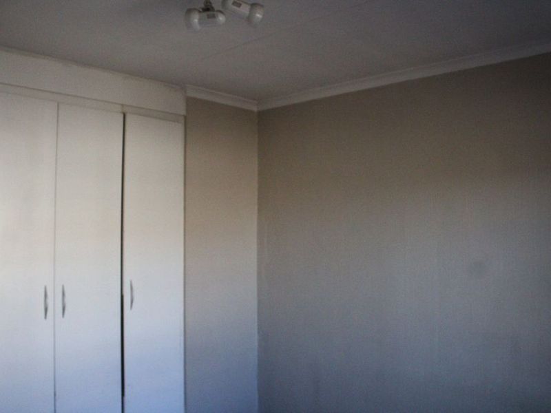An empty bedroom featuring neutral walls and built-in cupboards, providing a blank canvas for personalization.