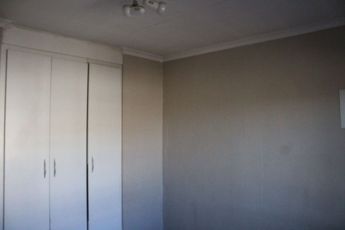 An empty bedroom featuring neutral walls and built-in cupboards, providing a blank canvas for personalization.