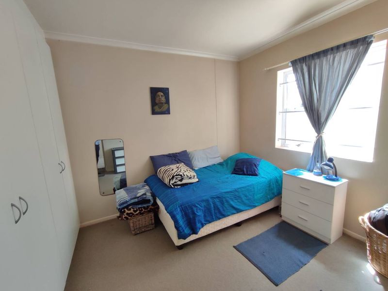 A functional bedroom featuring neutral wall tones, carpeted flooring, and built-in storage cupboards, offering a comfortable and practical living space.