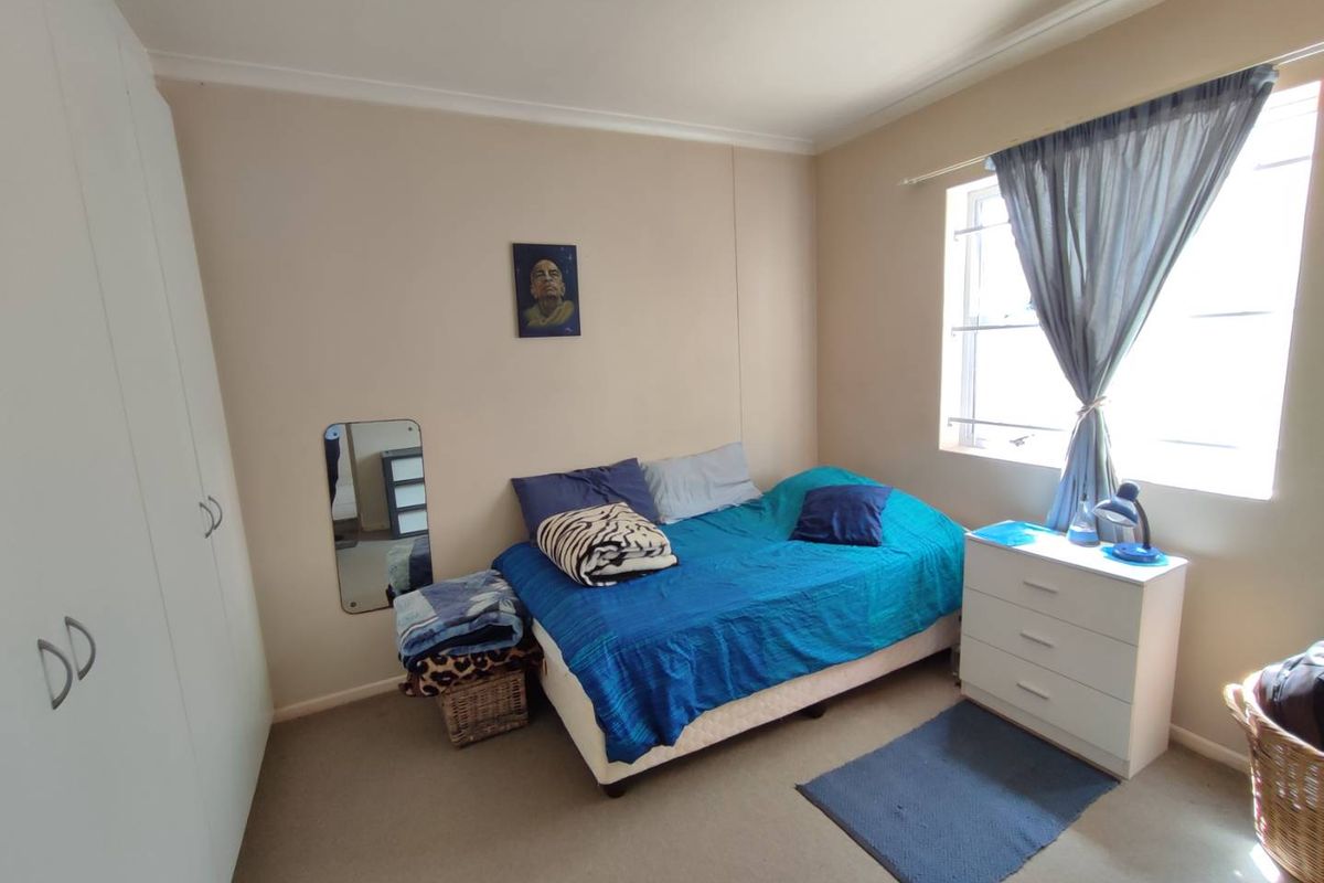 A functional bedroom featuring neutral wall tones, carpeted flooring, and built-in storage cupboards, offering a comfortable and practical living space.