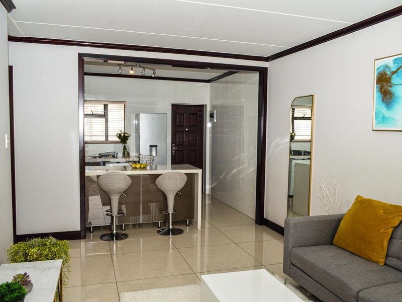 Open plan living area featuring a modern kitchen island, sleek tiled flooring, and clean finishes, creating a bright and functional space.