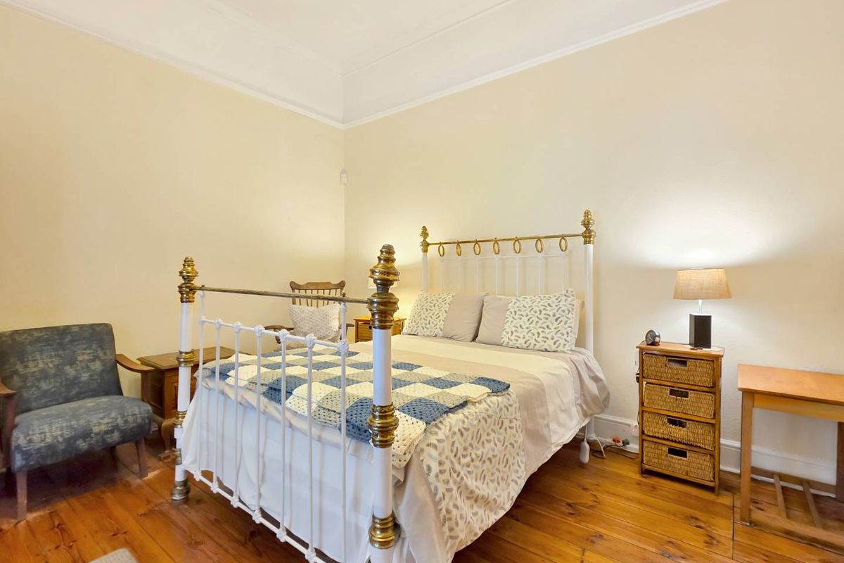 A well-proportioned bedroom featuring original timber floorboards, high ceilings with decorative cornicing, and classic skirting boards.