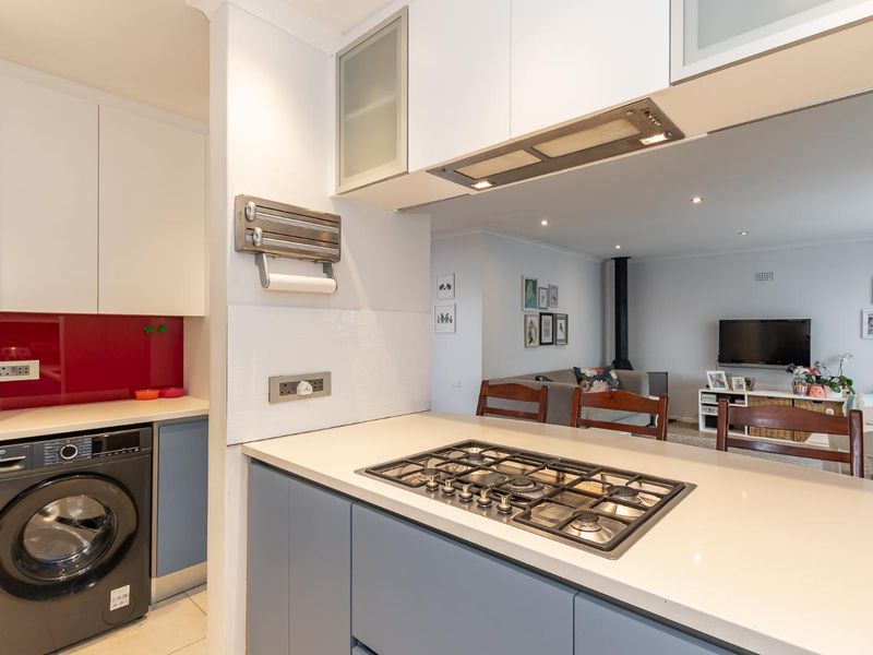 Modern kitchen featuring a gas cooktop, stone countertops, and integrated cabinetry, with an open-plan layout flowing into the adjacent living area.