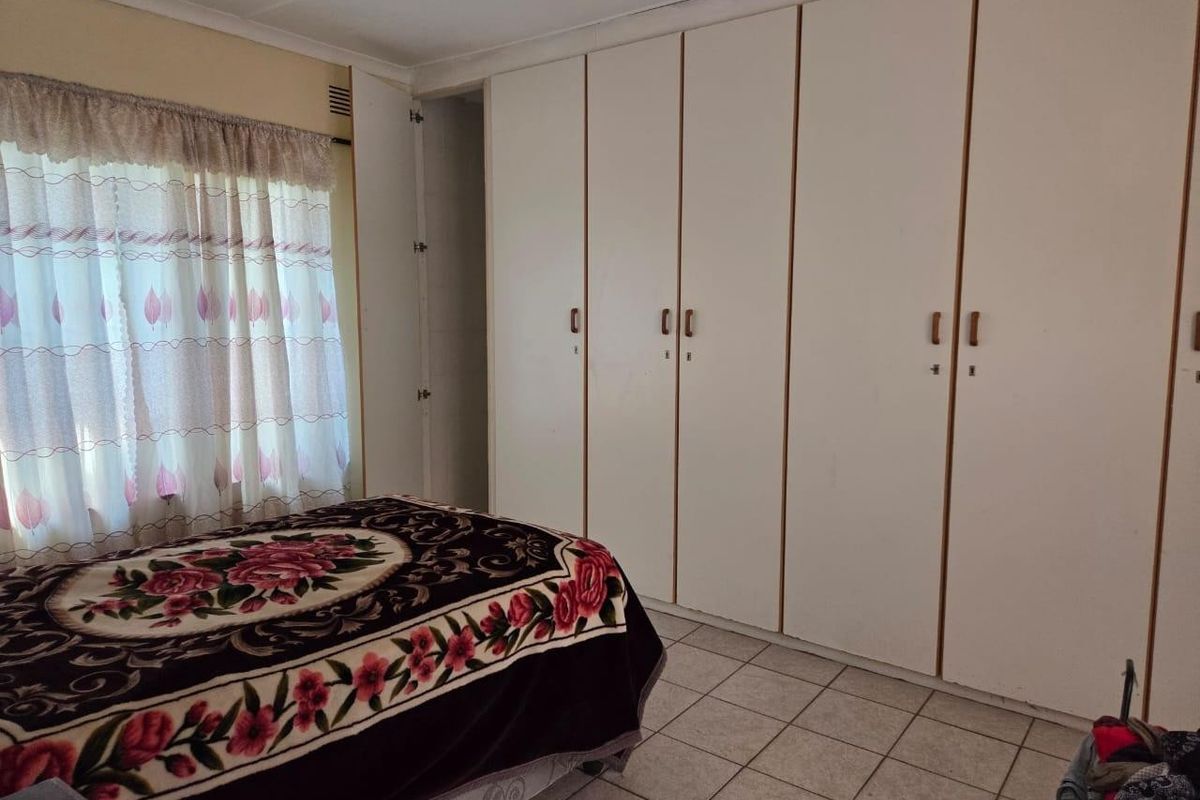 A bedroom featuring tiled flooring and extensive built-in cupboard storage, offering a functional space with potential for modern updates.