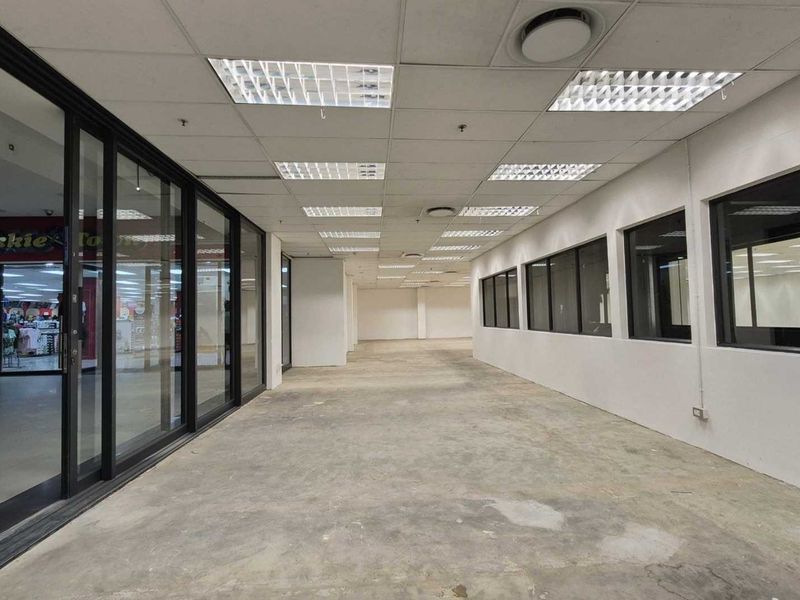 An empty, open-plan retail space featuring a suspended ceiling, recessed lighting, and a large glass storefront facade, ready for custom fit-out.
