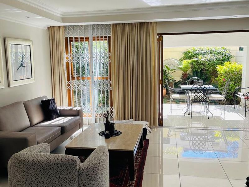 Bright living room featuring polished porcelain floor tiles, recessed lighting, and large sliding glass doors providing seamless access to the outdoor patio area.