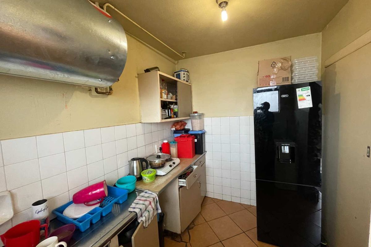 Compact kitchen area featuring tiled splashbacks, basic cabinetry, and exposed water heater unit.