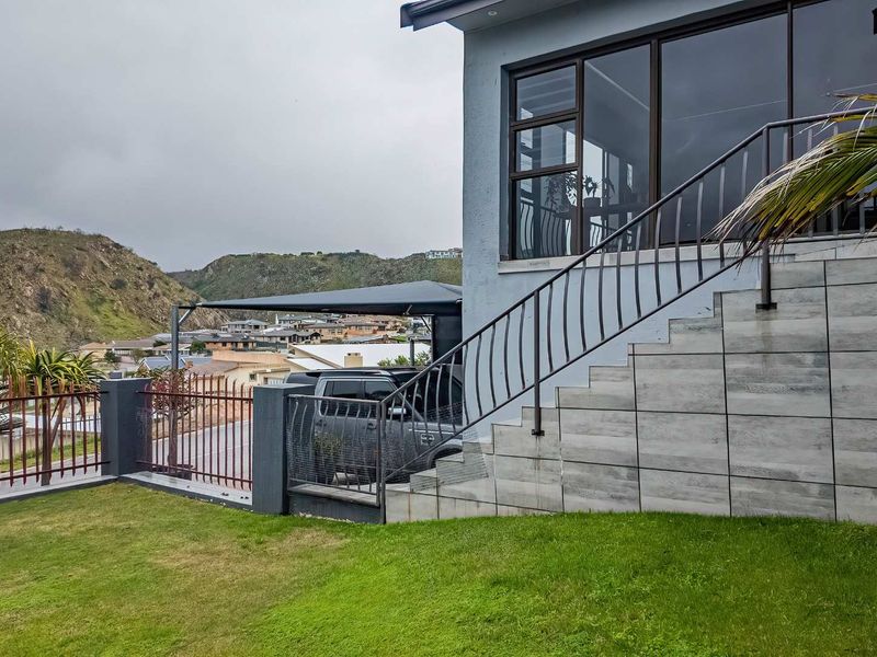 Exterior view of the property featuring a tiled staircase with metal balustrades, large windows, and a landscaped garden area.