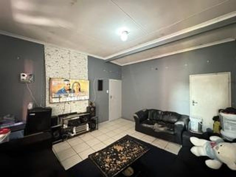 A living room featuring tiled flooring and neutral wall finishes, providing a functional space ready for cosmetic updates and modern styling.