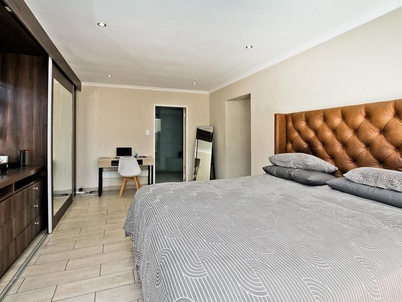 Spacious bedroom featuring tiled flooring, recessed downlighting, and a large built-in wardrobe with mirrored sliding doors.