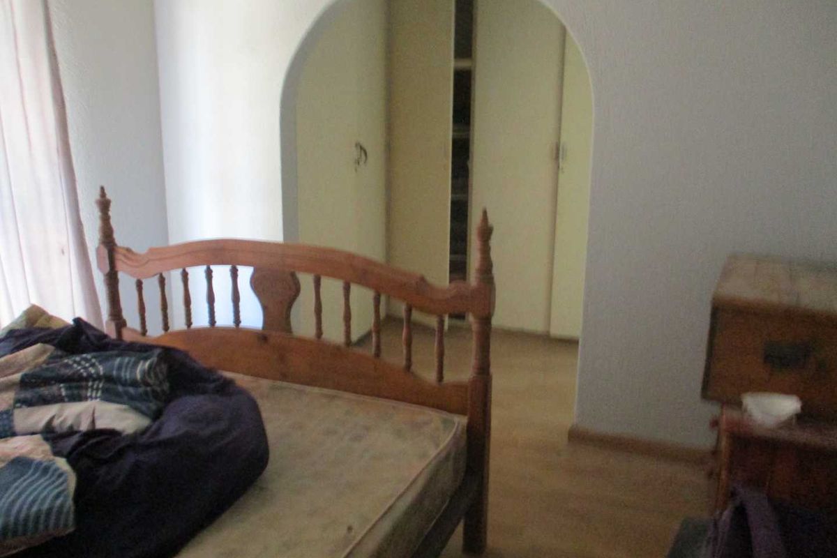 Bedroom featuring a distinctive arched entryway leading to a built-in closet area with laminate flooring.