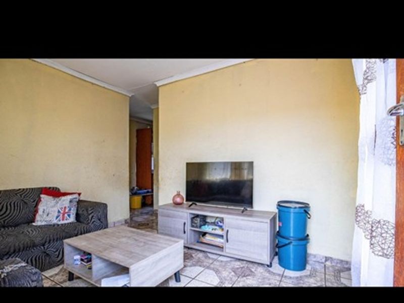 A living room area featuring tiled flooring and coved ceilings, requiring cosmetic updates to the wall finishes.