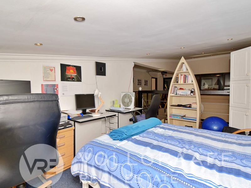 A bedroom featuring recessed downlights, coving, and carpeted flooring, currently utilized as a multi-purpose living and workspace area.