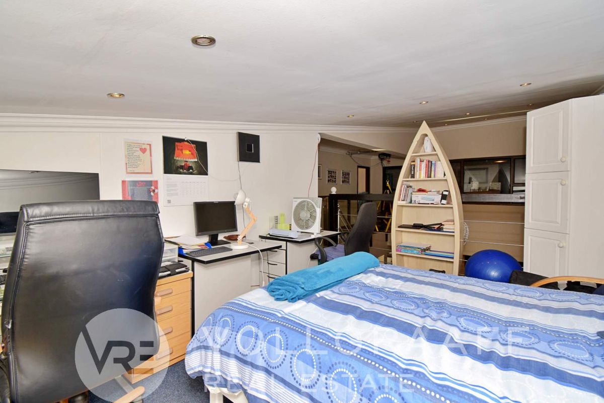 A bedroom featuring recessed downlights, coving, and carpeted flooring, currently utilized as a multi-purpose living and workspace area.