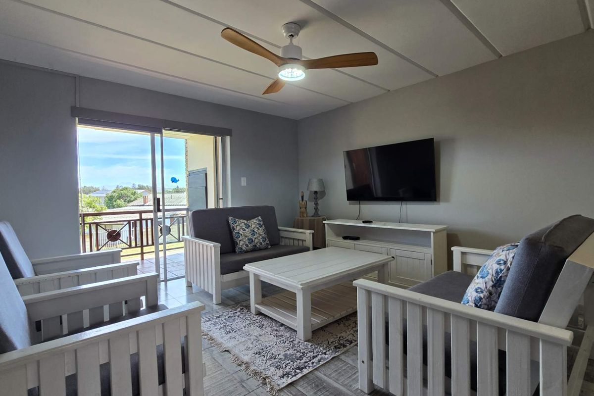 A bright living room featuring tiled flooring, a ceiling fan, and a sliding glass door providing access to an outdoor balcony area.