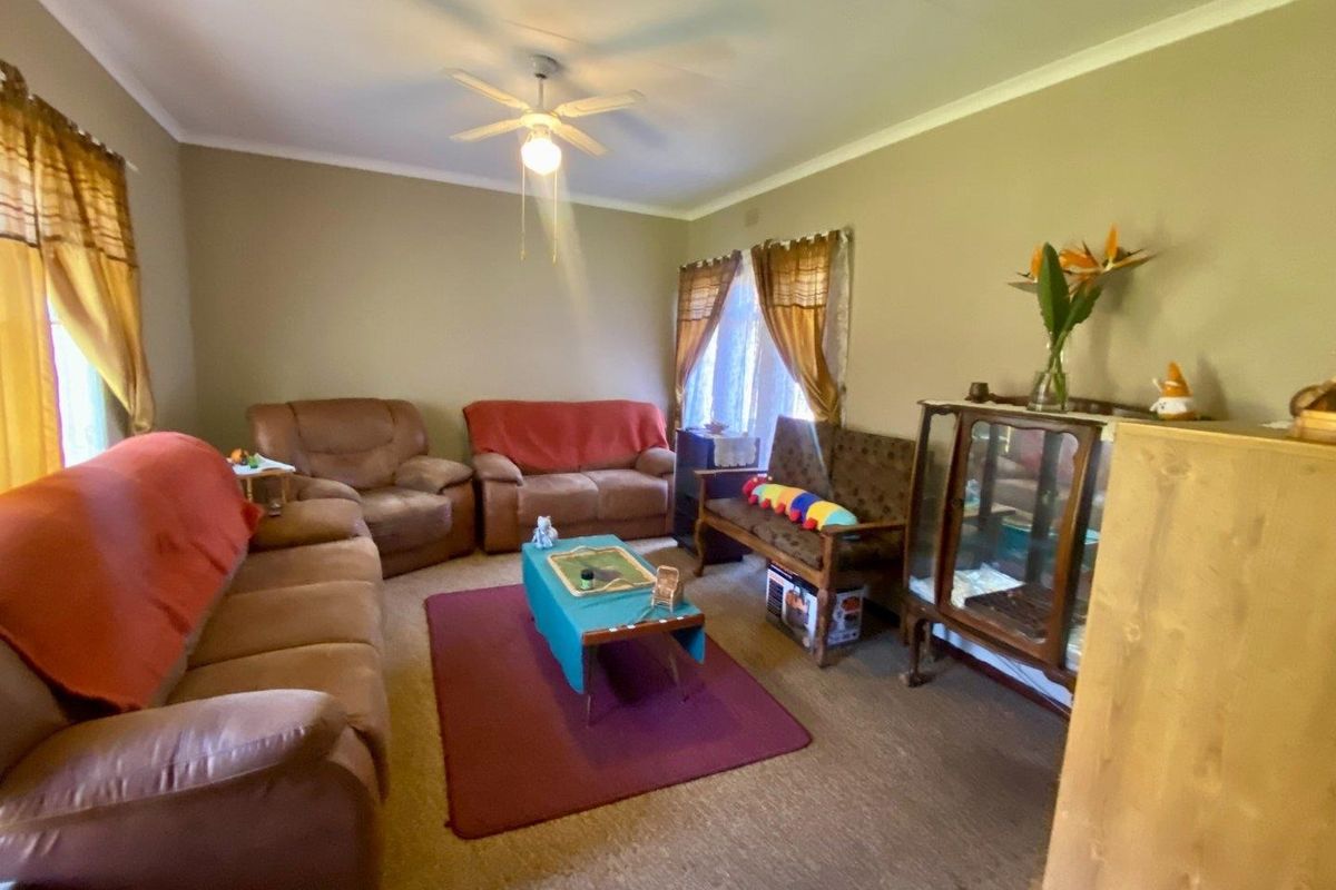 A spacious living room featuring neutral wall tones, carpet flooring, and a central ceiling fan, offering a comfortable and functional living space.