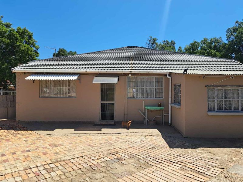 Rear exterior view of the house featuring a tiled roof, brick paved courtyard, and security-fitted windows and doors.