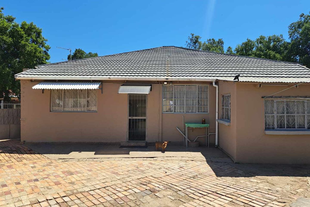 Rear exterior view of the house featuring a tiled roof, brick paved courtyard, and security-fitted windows and doors.