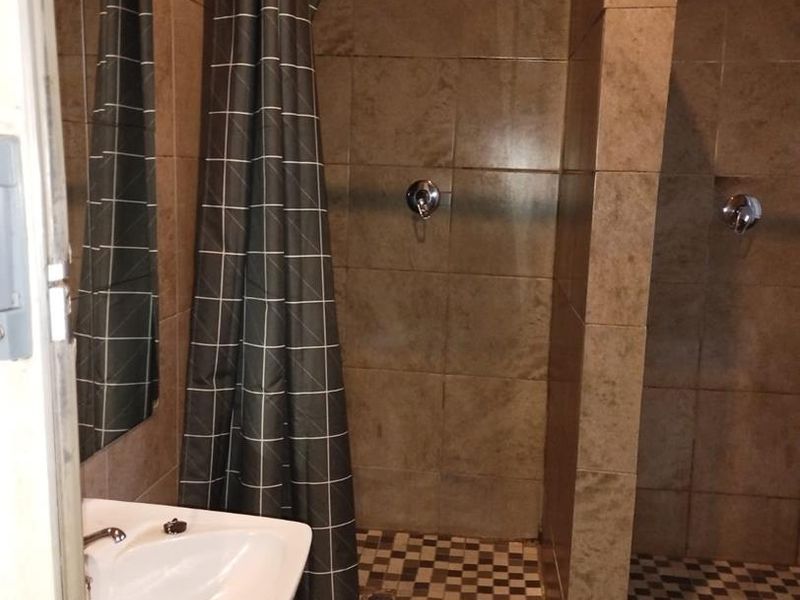 A functional bathroom featuring a pedestal basin and dual tiled shower enclosures with integrated shower mixers and heads.