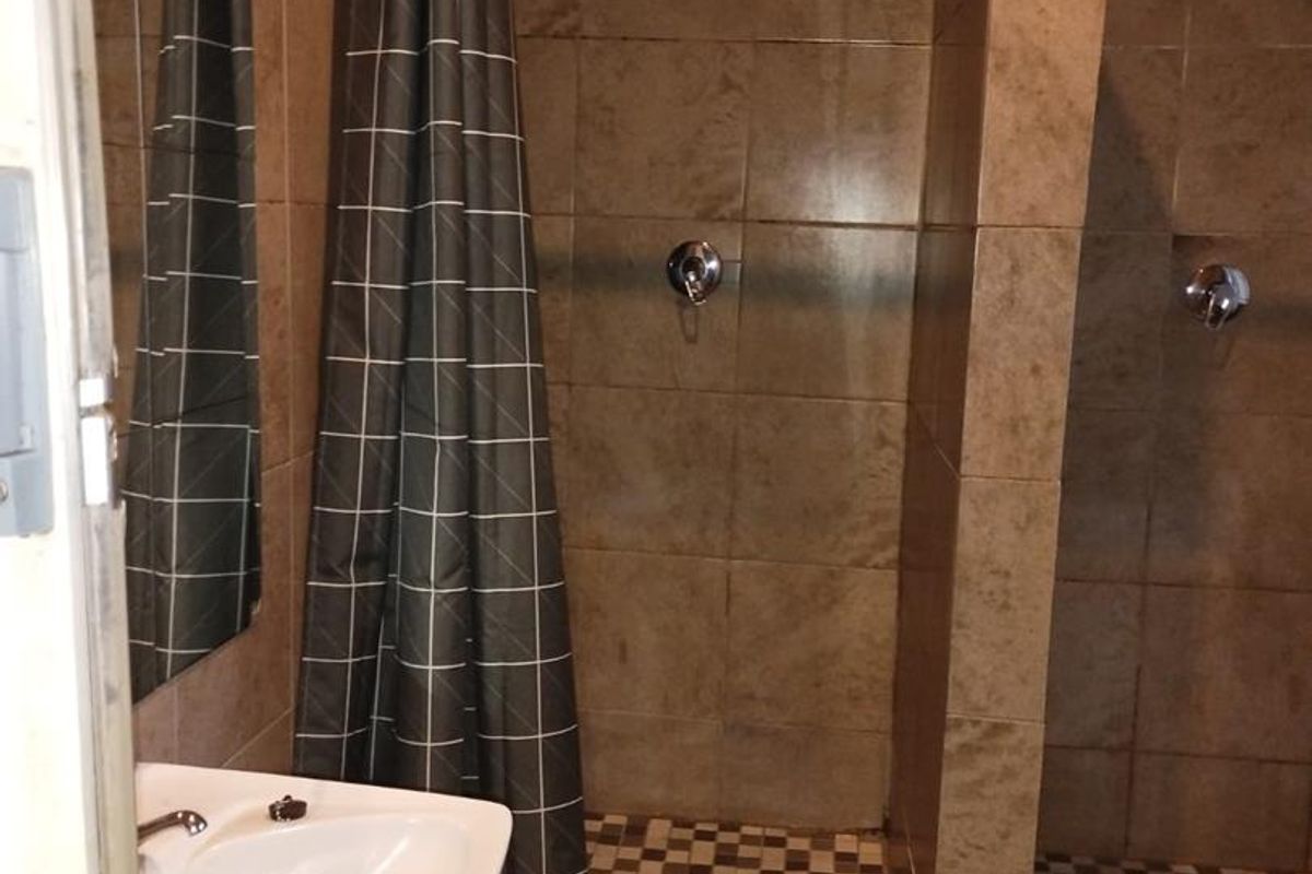 A functional bathroom featuring a pedestal basin and dual tiled shower enclosures with integrated shower mixers and heads.