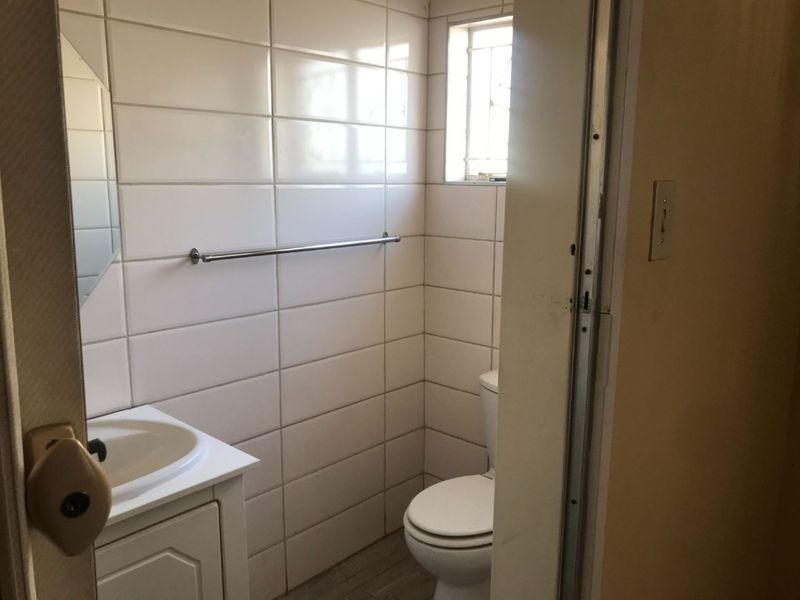 A compact bathroom featuring tiled walls, a vanity cabinet with a basin, and a standard toilet.
