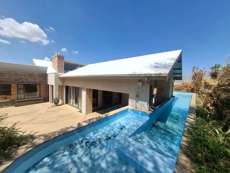 Outdoor area featuring a long swimming pool adjacent to a covered patio and a brick-accented home exterior.