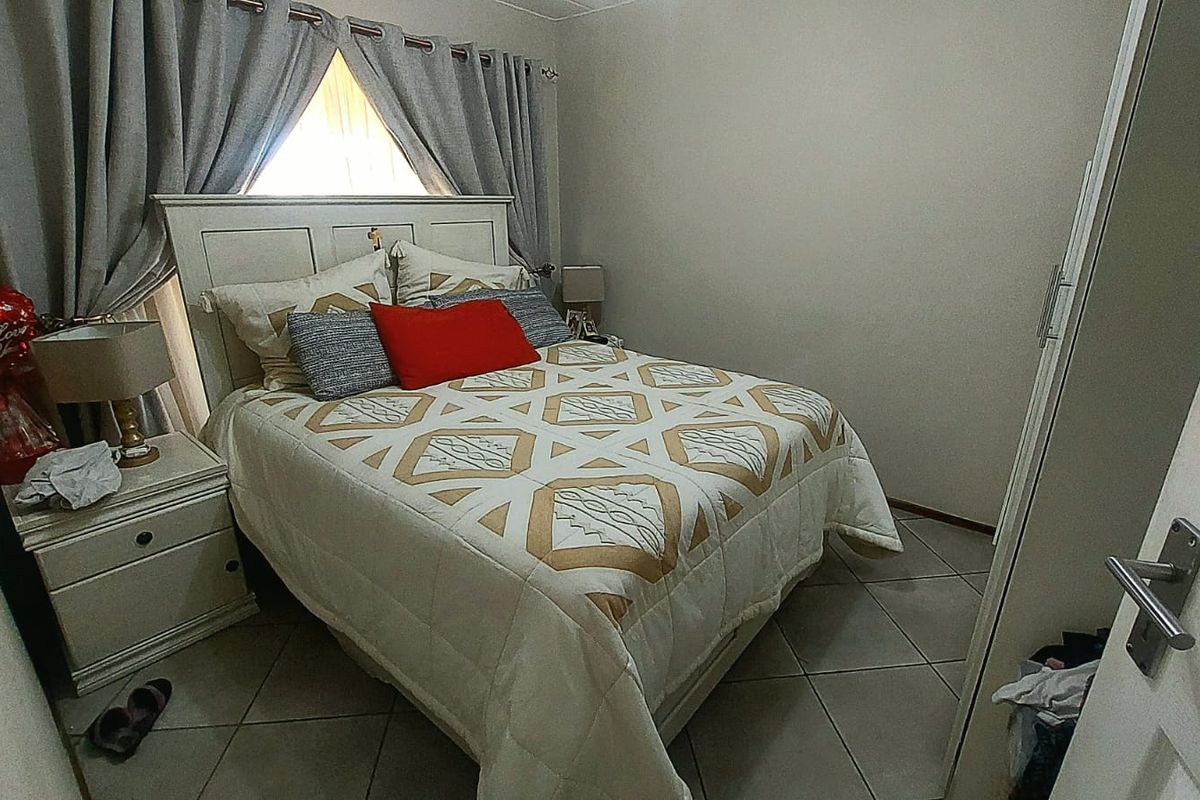 A cozy bedroom featuring tiled flooring and a built-in wardrobe, providing a functional and comfortable living space.