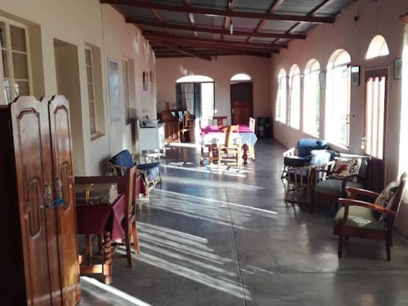 A spacious, covered patio area featuring polished concrete flooring, exposed timber roof beams, and multiple arched windows providing natural light.