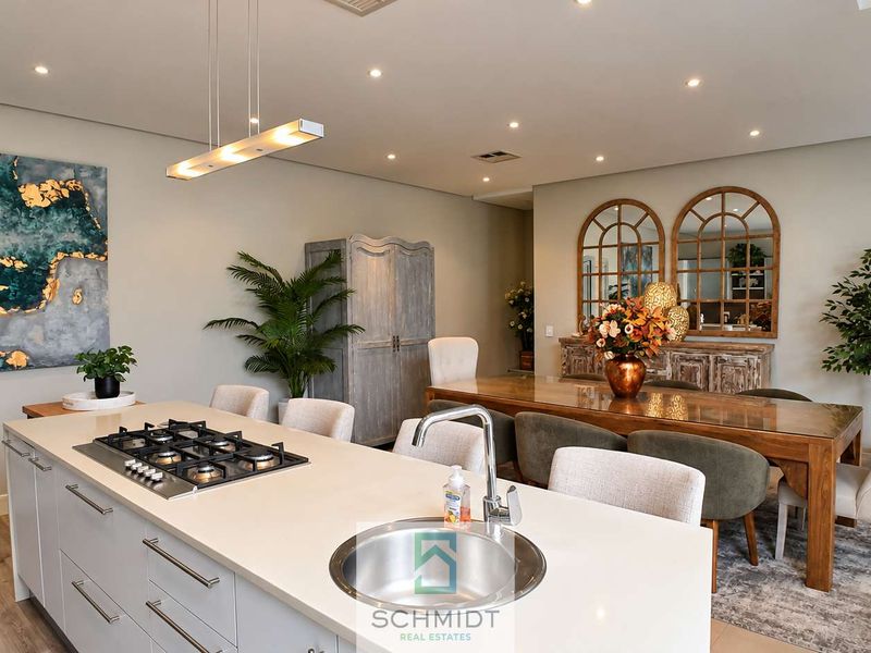 Modern open-plan living and dining area featuring a central kitchen island with a gas hob, integrated sink, and recessed lighting throughout.