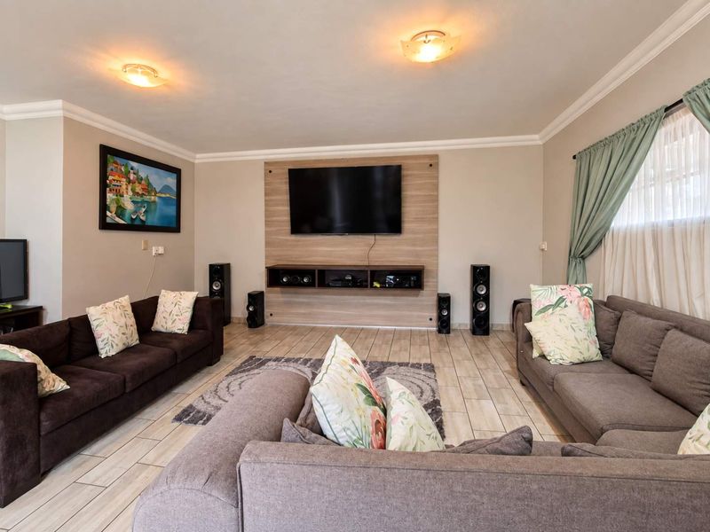 A well-maintained living room featuring tiled flooring, a modern built-in media wall unit, and decorative cove cornicing.