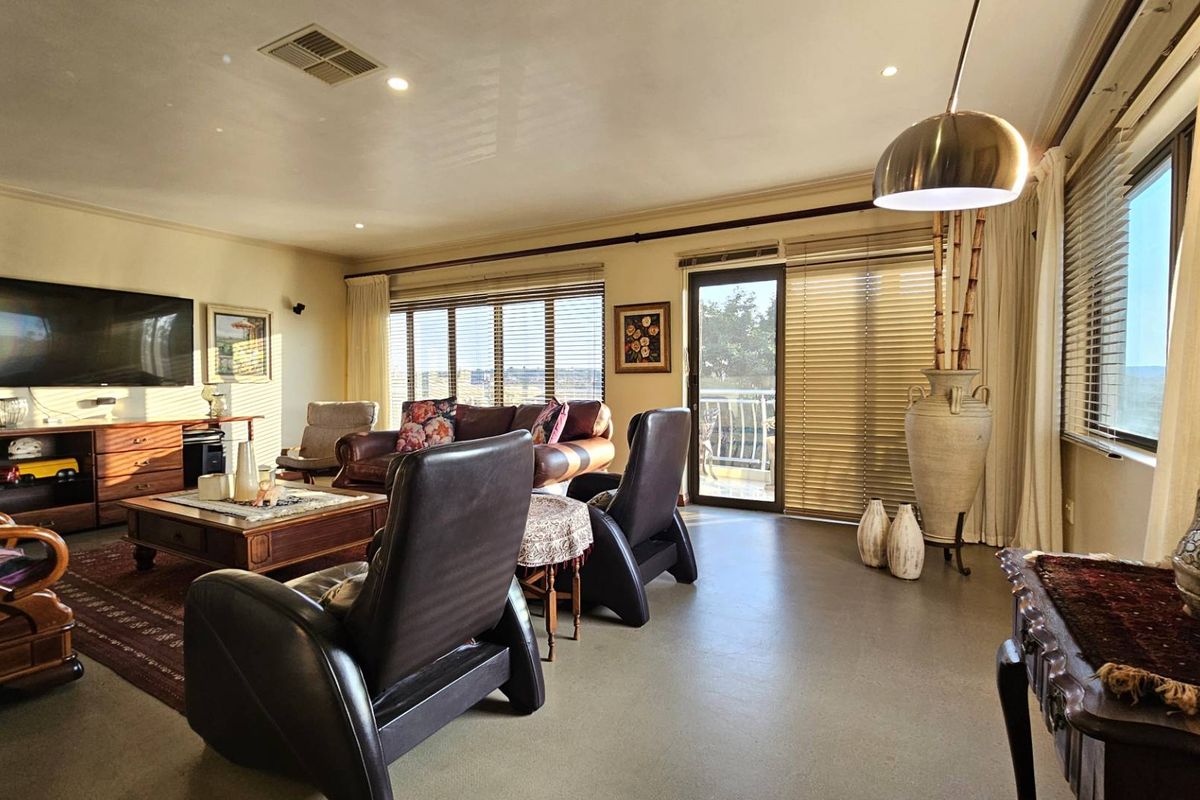 Spacious living room featuring recessed lighting, large windows with blinds, and direct access to an outdoor balcony area.