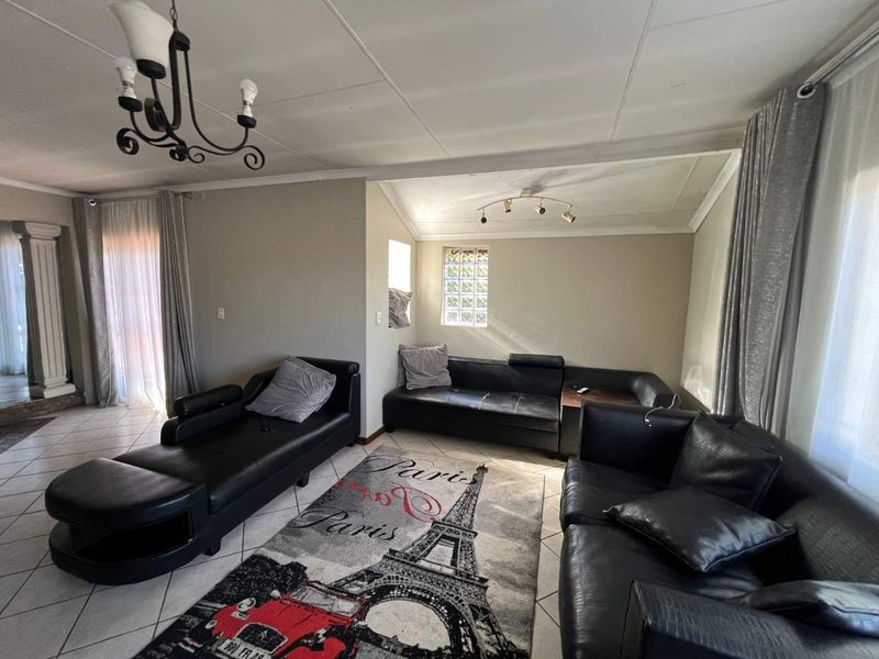 A spacious living room featuring tiled flooring, a unique glass block window, and coved ceilings, providing a functional base for modern interior updates.