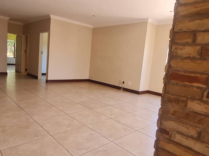 Spacious, open-plan living area featuring neutral tiled flooring and a prominent stone feature wall, offering a versatile blank canvas for interior design.