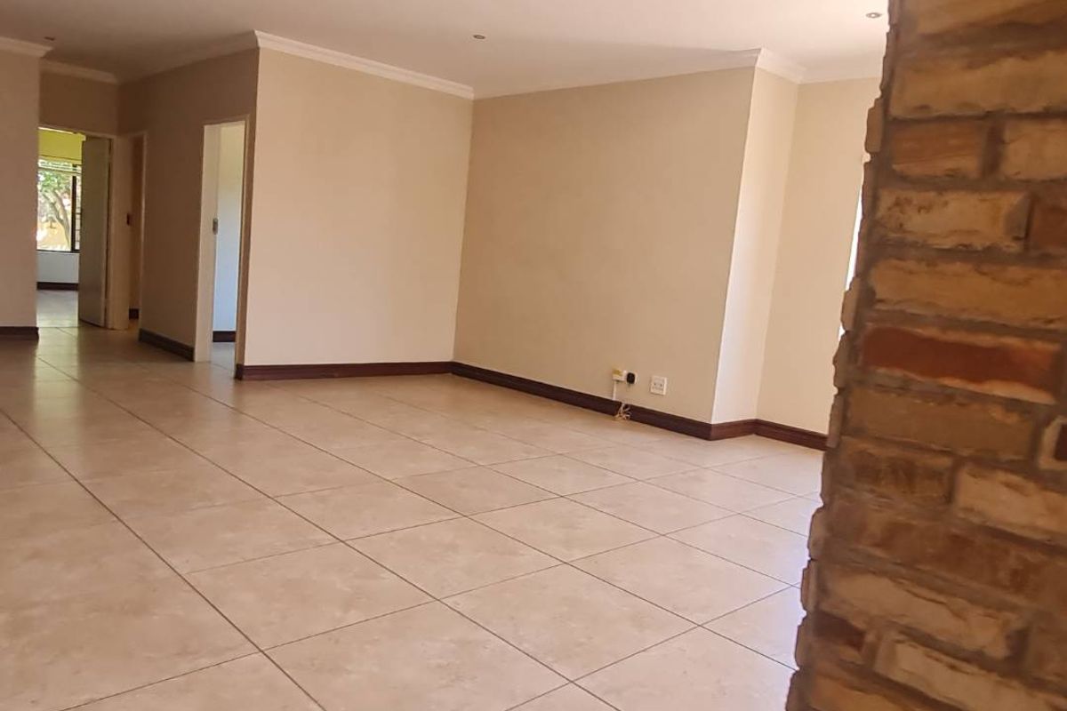 Spacious, open-plan living area featuring neutral tiled flooring and a prominent stone feature wall, offering a versatile blank canvas for interior design.