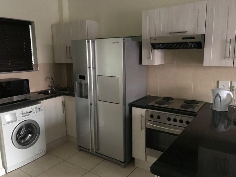 A functional kitchen featuring built-in cabinetry, a tiled backsplash, an electric hob with an extractor fan, and a built-in oven.