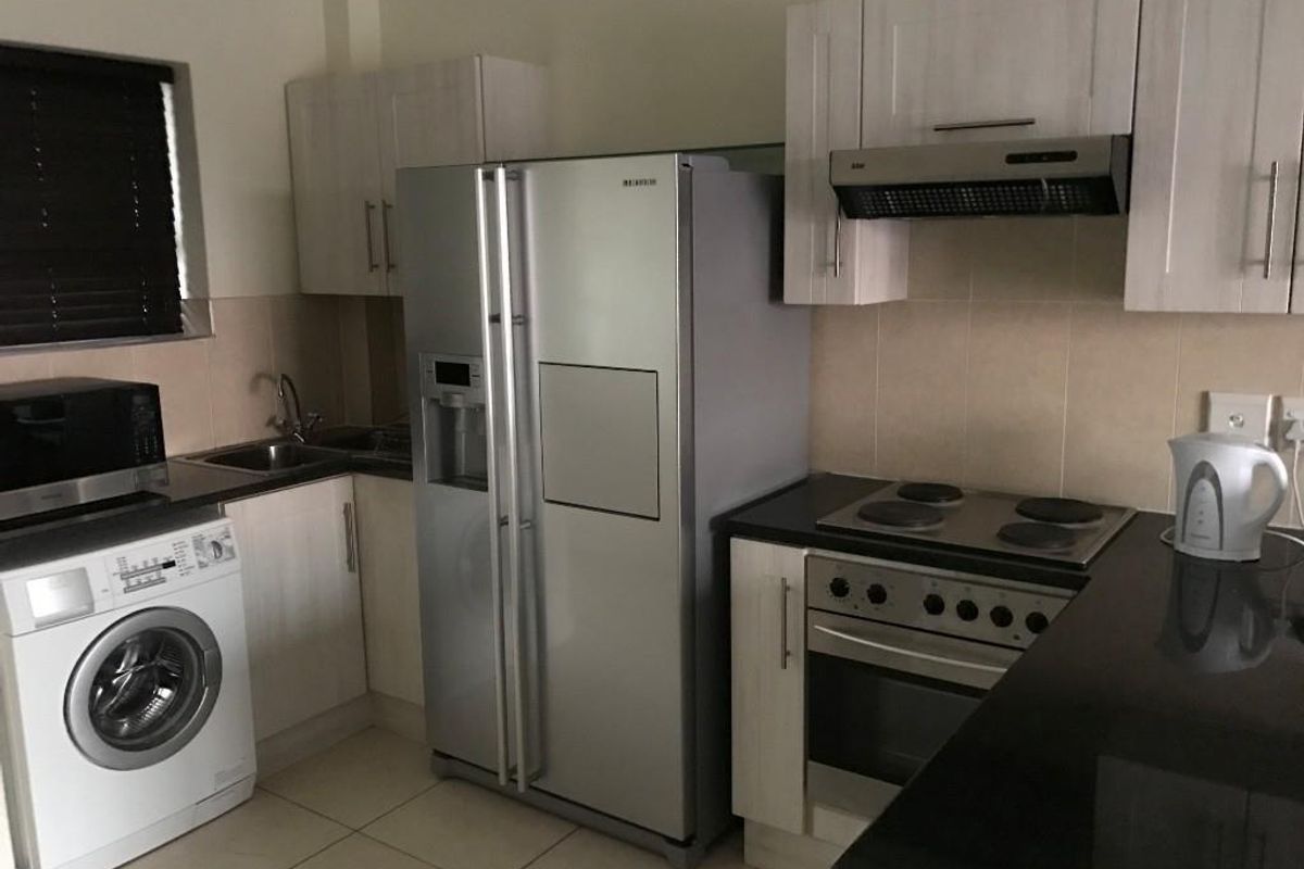 A functional kitchen featuring built-in cabinetry, a tiled backsplash, an electric hob with an extractor fan, and a built-in oven.