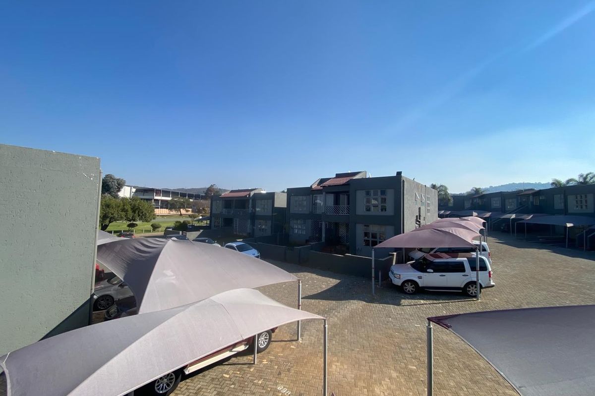 An elevated view of the townhouse complex parking area featuring paved driveways and multiple shade-cloth carports.