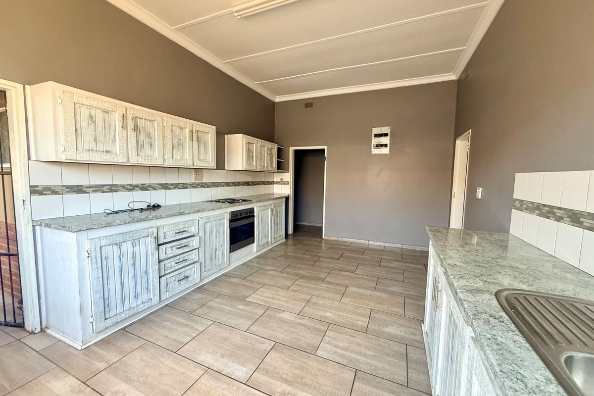 Spacious kitchen featuring granite countertops, built-in cabinetry, integrated oven and hob, and tiled flooring throughout.