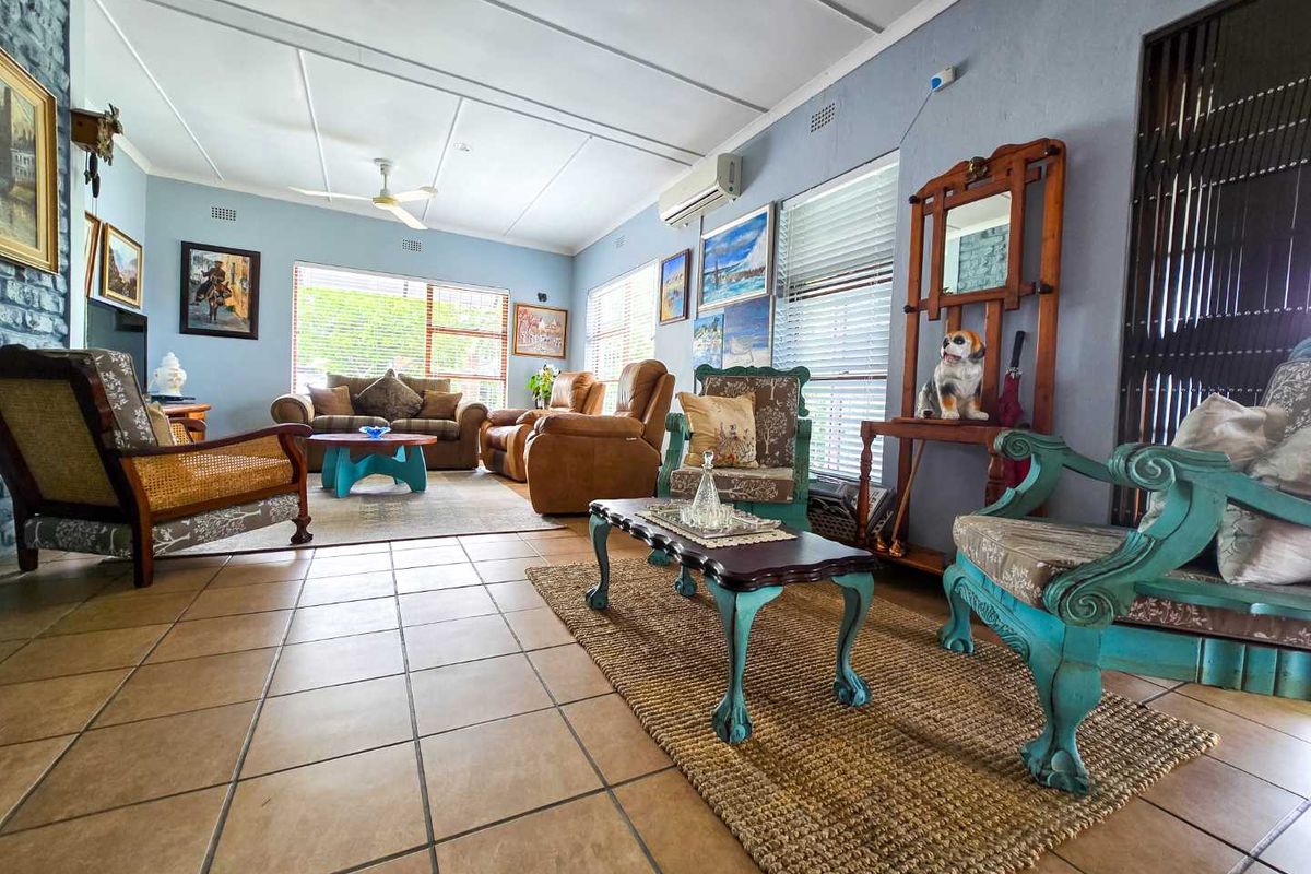 Spacious living room featuring tiled flooring, a ceiling fan, and a wall-mounted air conditioning unit, offering a comfortable and functional living space.